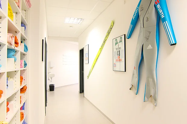Flur mit Skisprung-Ski, signiertem Rennanzug und Sporttrikots an der Wand