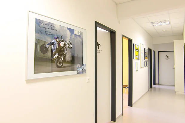 Heller Praxisflur des Therapiezentrums B12 mit gerahmten Sportbildern an der Wand