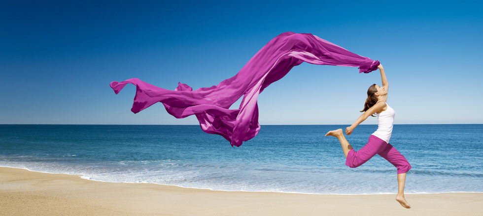 Frau am Strand läuft mit Tuch in der Hand